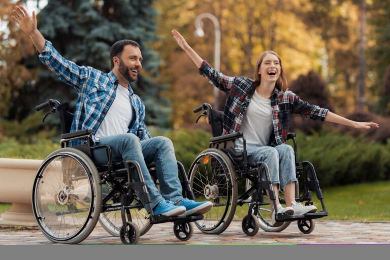 A man and a woman on wheelchairs ride around the park.