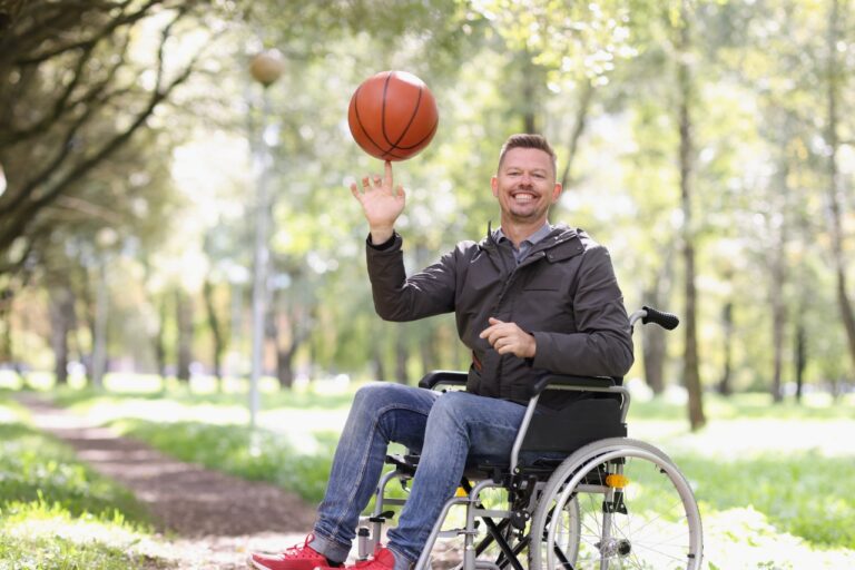 Smiling man in wheelchair holding basketball. Sports for disabled people concept